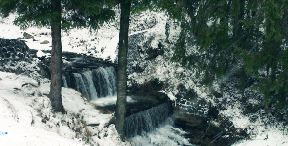 Waterfall in Snowing Winter Forest