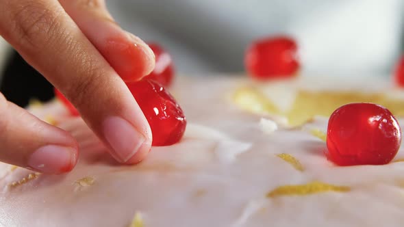 Woman topping a fresh baked cake with cherry