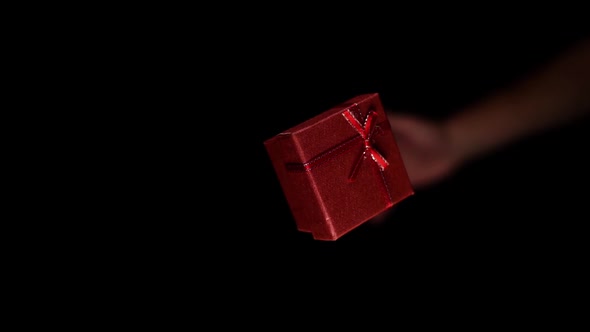Person Hand Throws Upward Small Paper Red Box with Ribbon