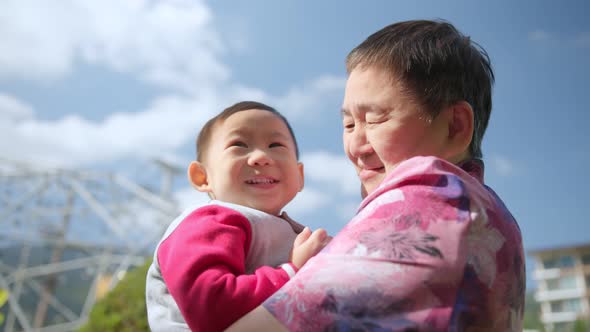 Happy asian family.Grandmother plays with her young nephew in the Park at daytime