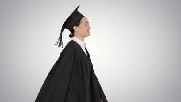 Smiling Female Student in Graduation Robe Walking with Her Diploma on Gradient Background