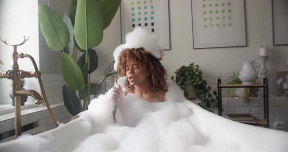 Funny Girl Sits in Bath Filled with Foam Holds Shower Singing Songs