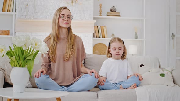 Caucasian Calm Mom Mother Blonde Young Adult Woman Sitting in Lotus Position on Sofa with Little