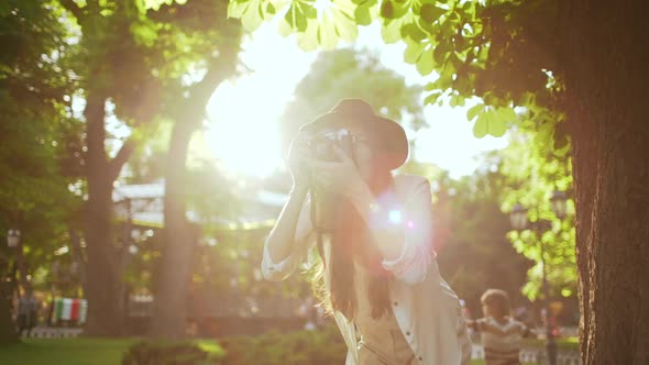 Young Beautiful Girl in Hat Photographing in City Park