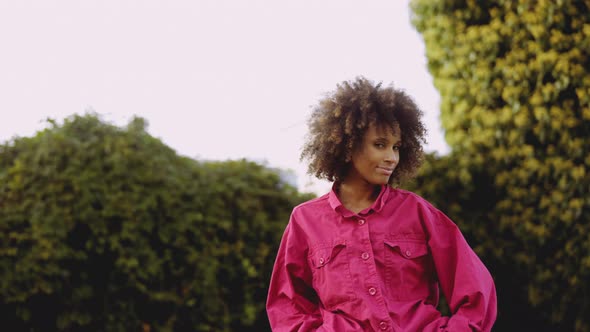 Smiling Young Woman With Afro Hair In Bright Pink Fashion