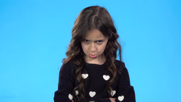 Girl Is Looking Unhappy, Offended and Crying Against Blue Background