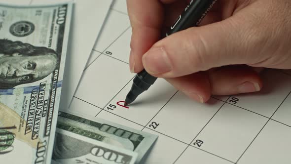 Female Hand Marking the PAY DAY in Calendar As a Reminder Using a Red Pen