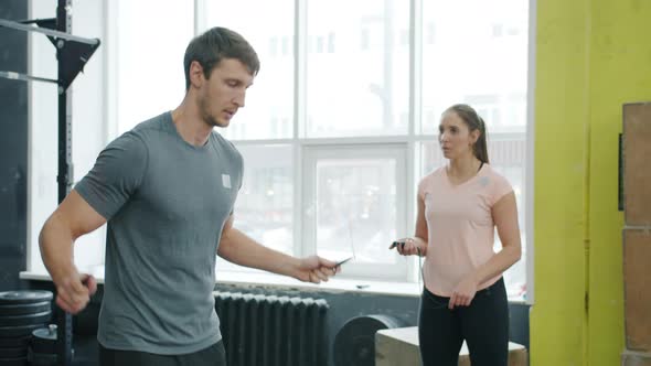 Slow Motion of Guy Jumping with Skipping Rope Exercising with Female Instructor in Gym