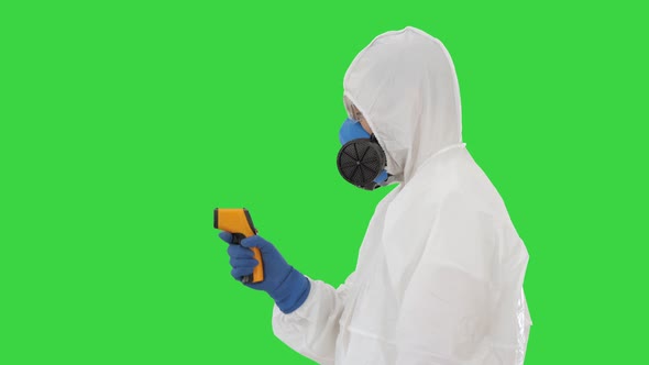 Temperature Check on a Corona Virus Doctor in Protective Suit with Pyrometer on a Green Screen