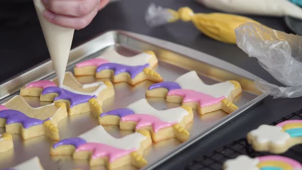 Step by step. Decorating unicorn sugar cookies with royal icing on baking sheet