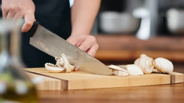 Closeup Professional Cook Person Hand Slicing Mushrooms on Wooden Board
