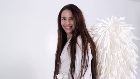 Brunette Girl in a White Dress with Angel Wings on a White Background in the Studio