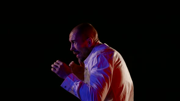 a Man in an Unbuttoned White Shirt Strikes with Hands Swings and Covers Face Against a Dark