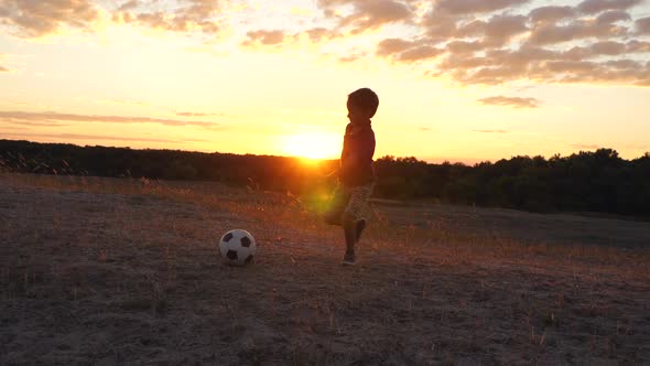 Silhouette of a Happy Child Playing Soccer in the Park During Sunset. Active Lifestyle and Games