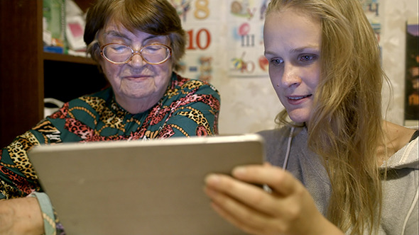 Young And Senior Woman Looking Through Photos alt