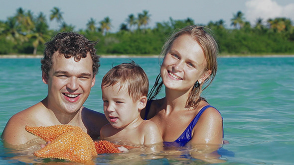 Parents And Son In Sea Water Holding Starfish
