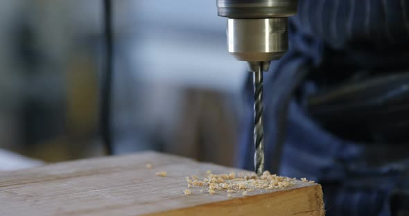 Carpenter drilling wooden plank with machine in workshop 4k