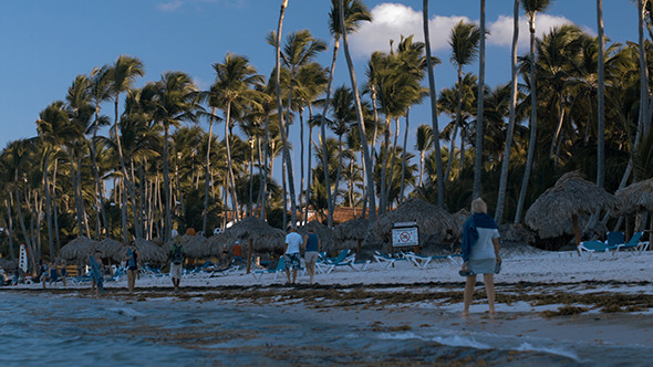 People Walking Along The Beach On Tropical Resort