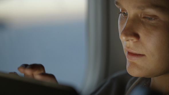 Woman Using Pad During Flight And Looking Out alt