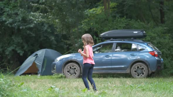 Little child girl dancing happily at campground in summer.