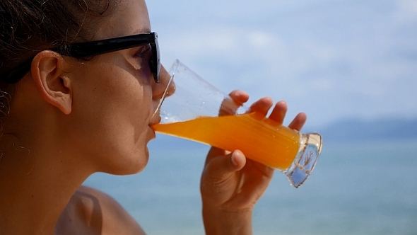 Woman Drinking Juice against Sea