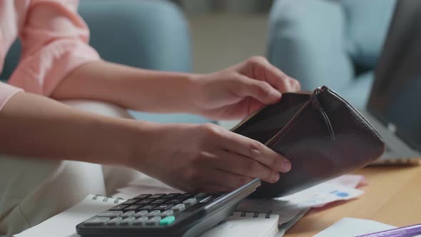 Close Up Of Woman's Hand Calculating Money By Calculator Before Opening The Purse To Check Money