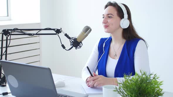 Concept of Streaming and Broadcasting. Young Woman Wearing Headphones and Talking at Online Radio