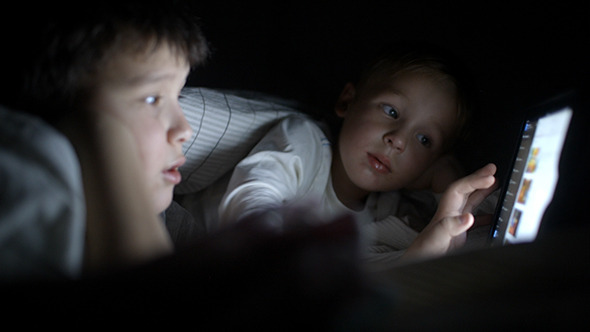 Two Boys Watch Film At Night Using Tablet