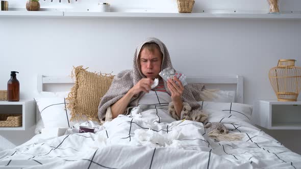 Sick Man Holding Pack of Pills and Coughing