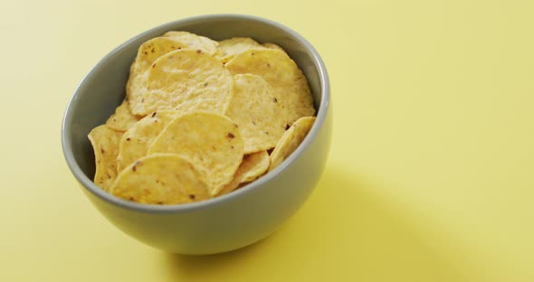 Close up of chips in a bowl with copy space on yellow surface