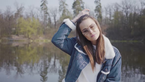 Portrait of Pretty Young Glamour Smiling Woman in Fashionable Glasses and Jeans Jacket Looking in