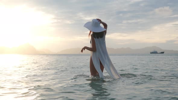 Young Woman In Bikini And Sun Hat In Sea At Sunset