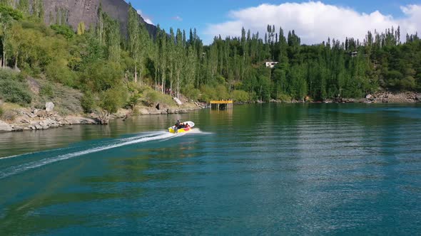 aerial drone of pakistani tourists in the mountain forest of Skardu Pakistan taking a motor boat rid