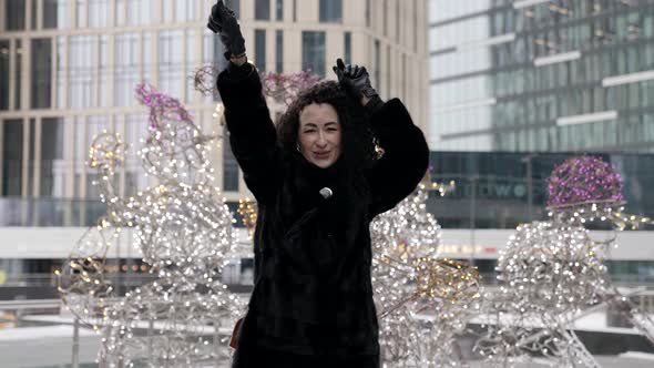 A Curlyhaired Woman in a Fur Coat Walking Around a Modern City Enjoying a Beautiful Day