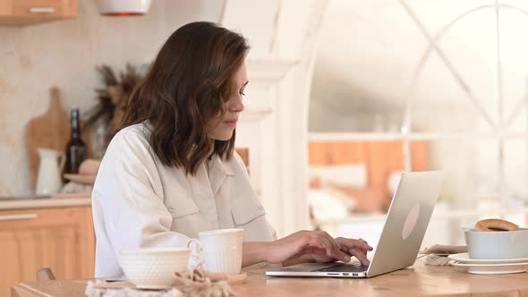 Attractive Woman Working on Laptop Seated at Desk in Cozy Living Room