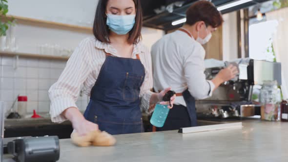 Asian attrctive young couple wear face mask disinfecting wiping and rubbing on counter in restaurant