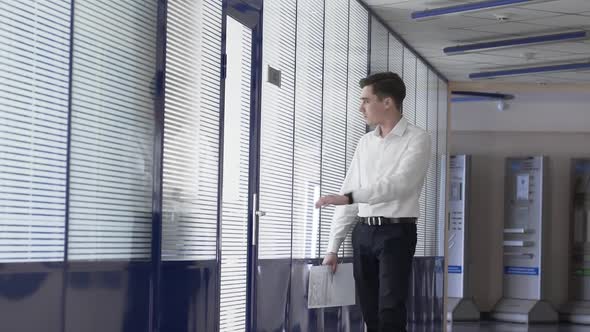 Slow Motion of Man Walks Down a White Glass Corridor in an Under Construction Office Building