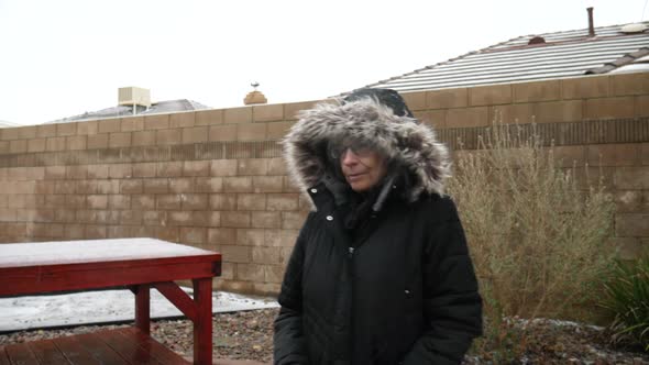 A woman in a warm winter coat walking in a snow and hail storm in the frozen cold winter season SLOW