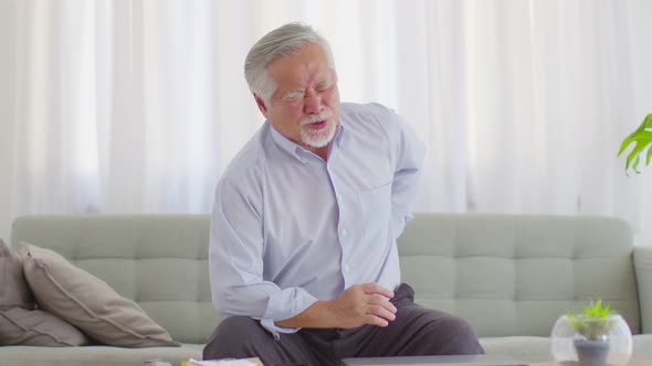 Asian Elderly senior man back pain and illness on sofa at home,Elderly Care Concept