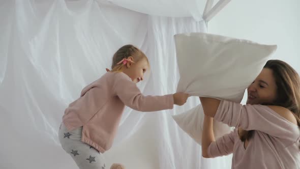 Mom and Little Daughter Fight with Pillows