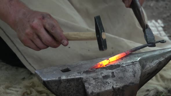 Blacksmith makes a knife, sword war and forging the hot glowing iron with a hammer on an anvil