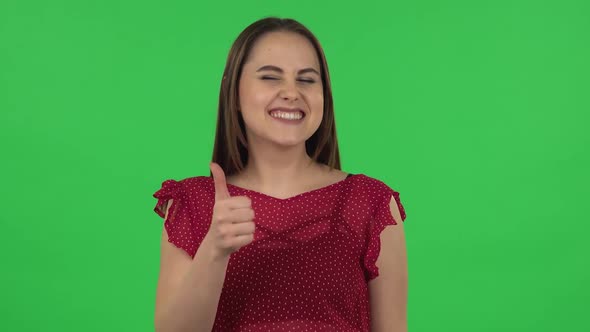 Portrait of Tender Girl in Red Dress Is Showing Thumbs Up, Gesture Like. Green Screen
