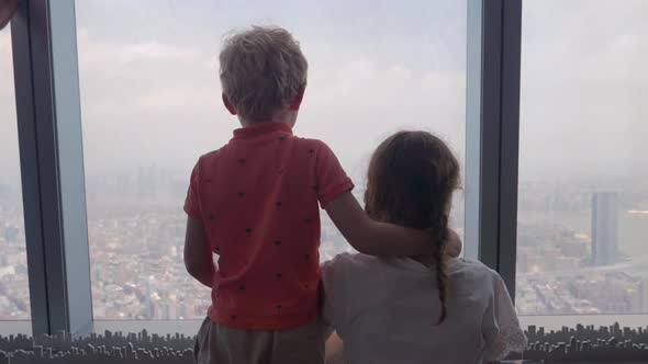 Boy And Sister Looking Through Window To New York City Below