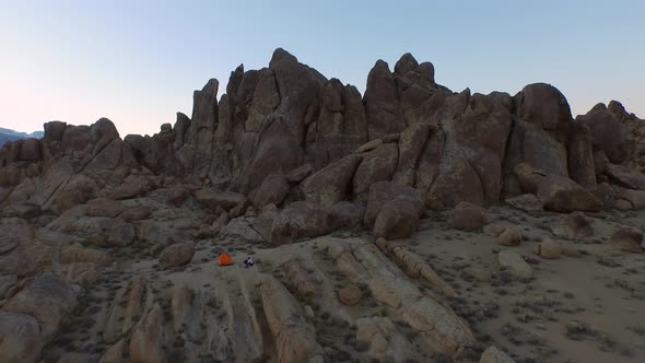 Aerial shot of a young man backpacker camping with his dog in a mountainous desert.