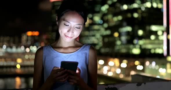 Woman use of mobile phone in city at night 