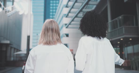 Two young women in business attire walk away with a bike in a business area