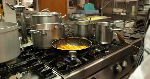 Cooking Penne Pasta In A Skillet Over The Stove With Medium Heat - zoom-in shot, slow motion