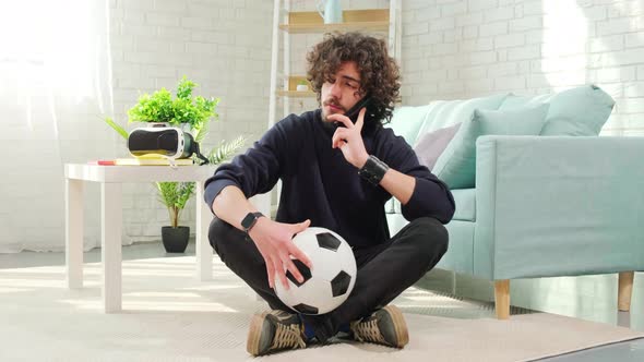 Man Standing with Soccer Ball in Hands and Talking on the Phone