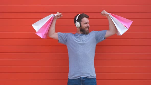 Portrait of a Positive Hipster Beard Man Holding Pink and White Shopping Bag on Red Background. Man