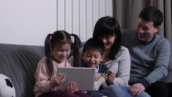 Happy Asian Family Watching Cartoons on Tablet Pc
